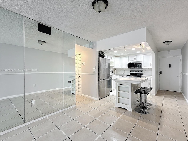 kitchen featuring light tile patterned floors, white cabinetry, a kitchen breakfast bar, stainless steel appliances, and a center island