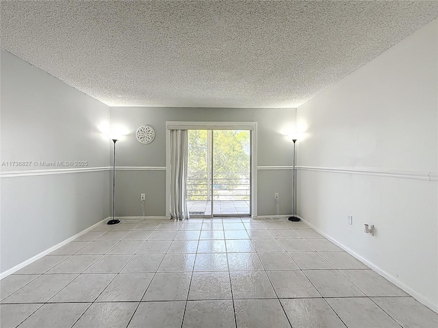 empty room with a textured ceiling and light tile patterned floors