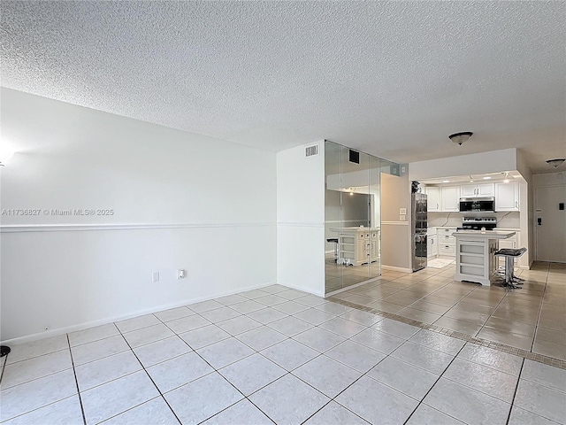 tiled spare room with a textured ceiling