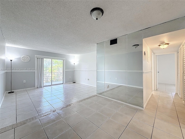 tiled empty room featuring a textured ceiling