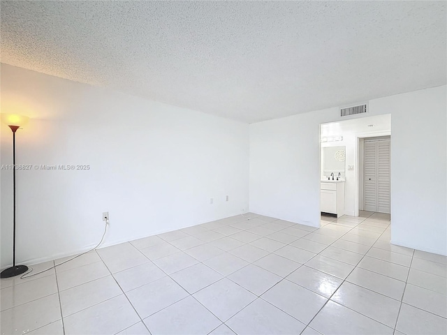 tiled empty room featuring a textured ceiling