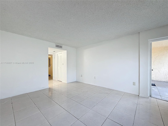 spare room featuring light tile patterned floors and a textured ceiling