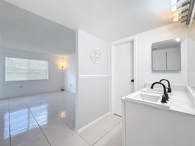 laundry room featuring light tile patterned flooring, sink, and a textured ceiling