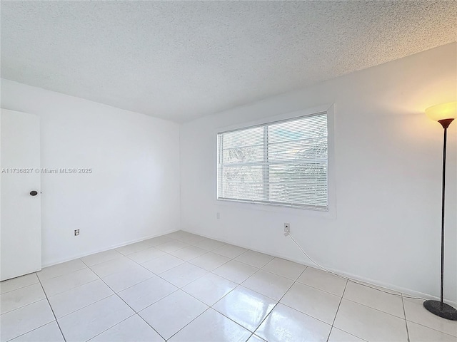 unfurnished room with a textured ceiling and light tile patterned flooring