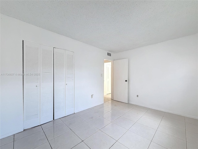 unfurnished bedroom featuring a closet, a textured ceiling, and light tile patterned flooring