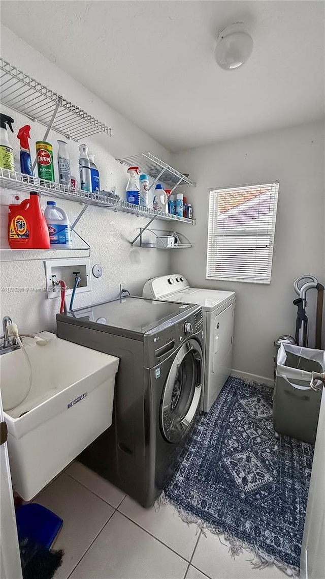 clothes washing area featuring laundry area, independent washer and dryer, a sink, and tile patterned floors