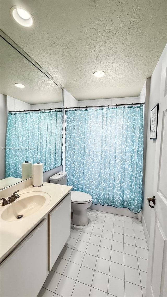 bathroom featuring toilet, tile patterned floors, a textured ceiling, and vanity