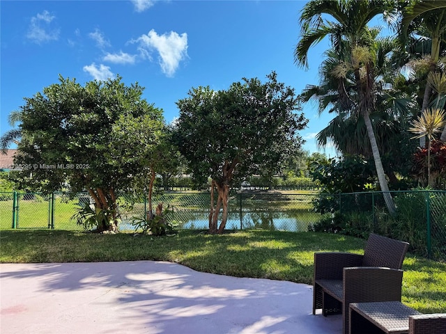 view of patio with a water view and fence