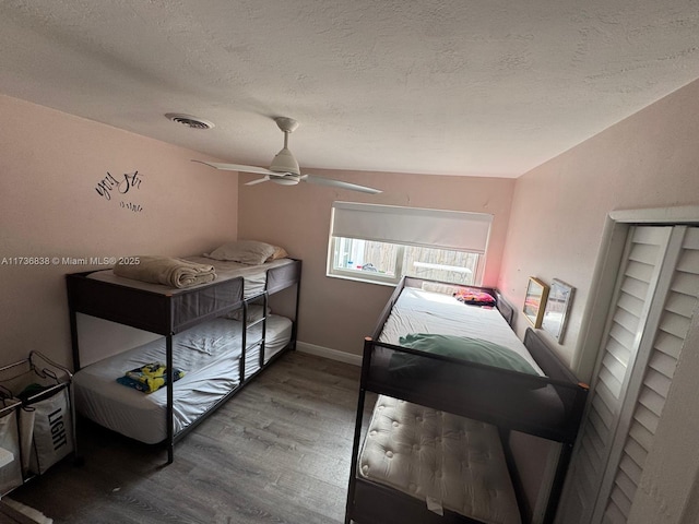 bedroom featuring hardwood / wood-style flooring, a textured ceiling, and ceiling fan