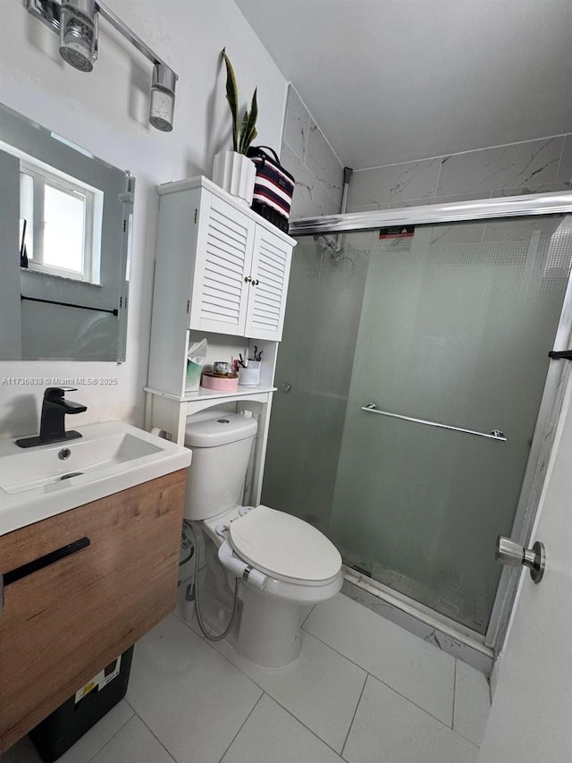 bathroom with vanity, toilet, a shower with shower door, and tile patterned flooring