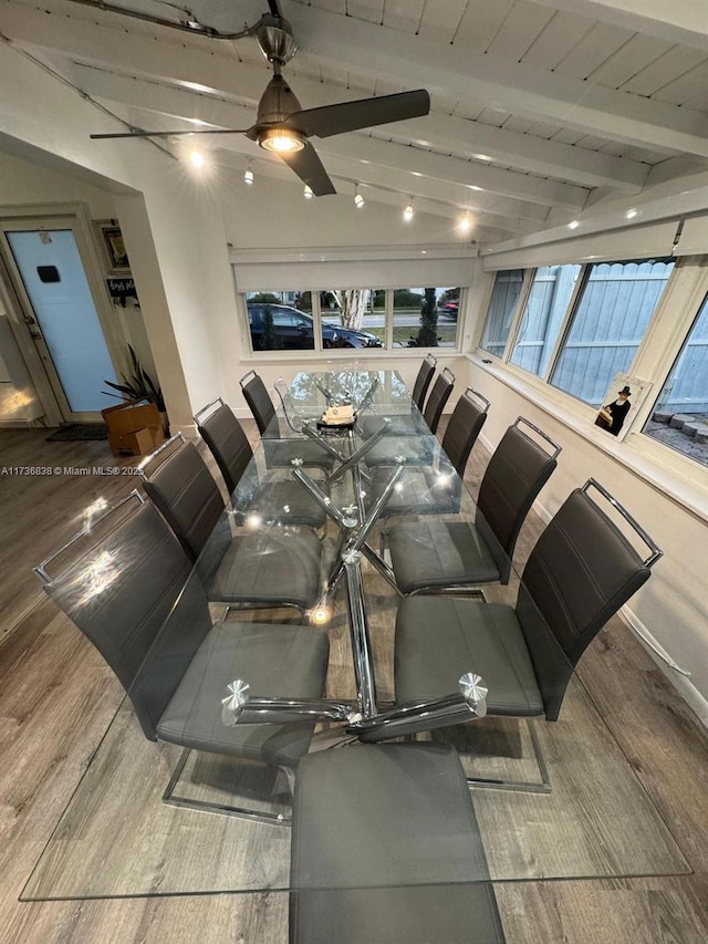 dining space with hardwood / wood-style flooring and vaulted ceiling with beams