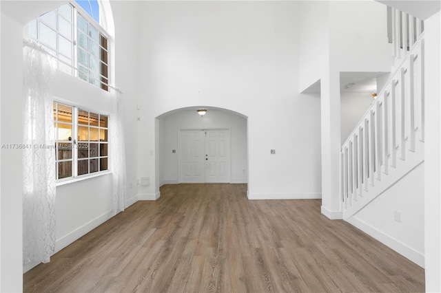 unfurnished living room with light hardwood / wood-style flooring, plenty of natural light, and a high ceiling