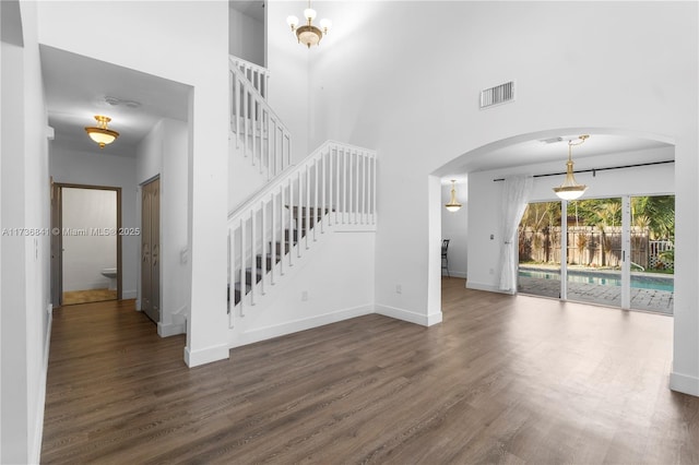 unfurnished living room featuring dark wood-type flooring and a towering ceiling