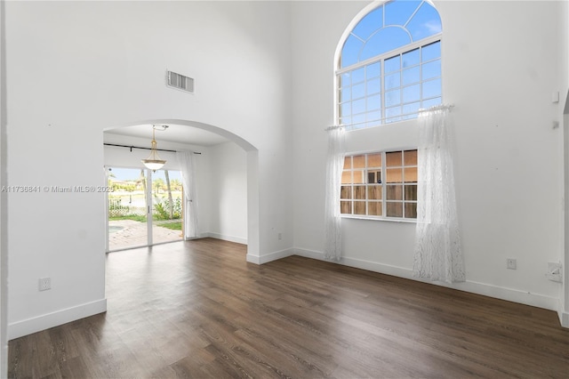 spare room with a towering ceiling and dark hardwood / wood-style flooring