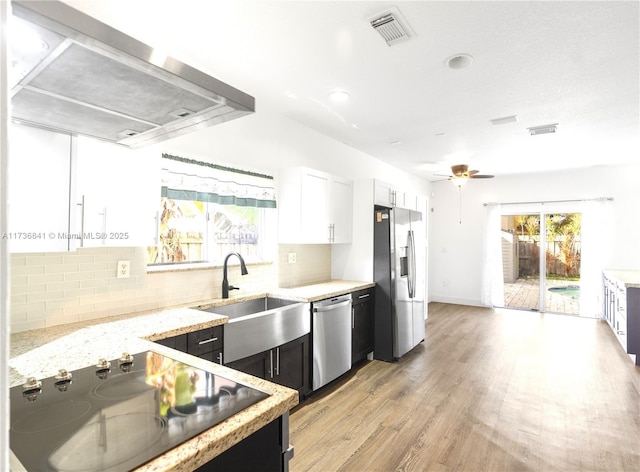 kitchen featuring extractor fan, tasteful backsplash, sink, white cabinets, and stainless steel appliances