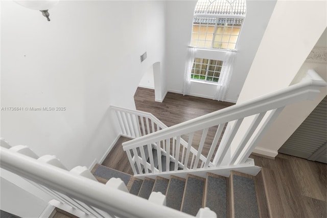 staircase featuring hardwood / wood-style flooring and a towering ceiling