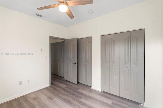 unfurnished bedroom featuring ceiling fan, two closets, and light hardwood / wood-style floors