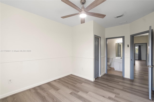 unfurnished bedroom with connected bathroom, sink, hardwood / wood-style flooring, and ceiling fan