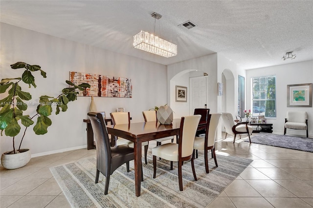 dining area with a chandelier, a textured ceiling, and light tile patterned floors