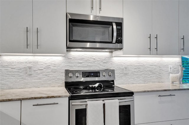 kitchen featuring light stone counters, backsplash, stainless steel appliances, and white cabinets