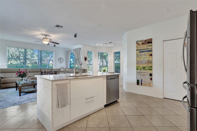 kitchen featuring sink, light tile patterned floors, appliances with stainless steel finishes, a kitchen island with sink, and white cabinets