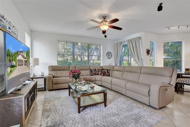 tiled living room with ceiling fan, plenty of natural light, and a textured ceiling