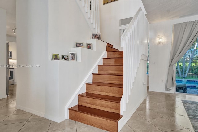 staircase featuring tile patterned flooring and a high ceiling