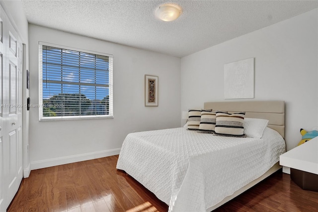 bedroom with dark hardwood / wood-style floors and a textured ceiling