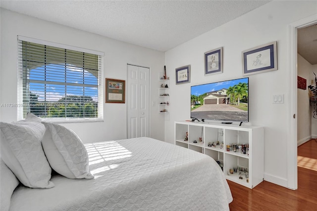 bedroom with wood-type flooring, a textured ceiling, and a closet