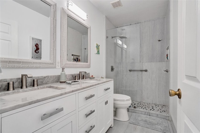 bathroom with vanity, tiled shower, and toilet