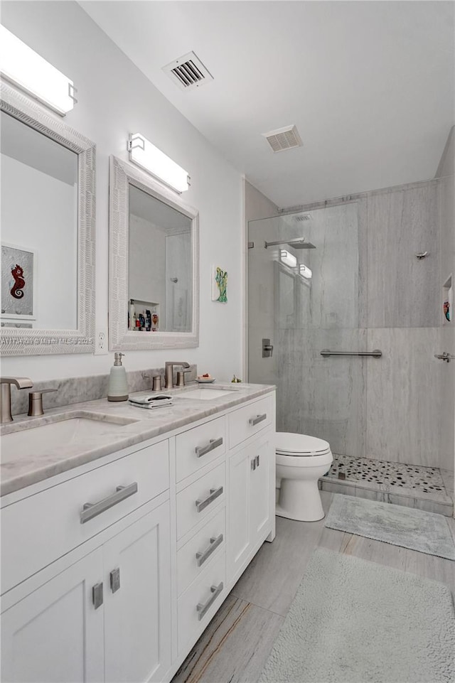 bathroom featuring vanity, a tile shower, and toilet