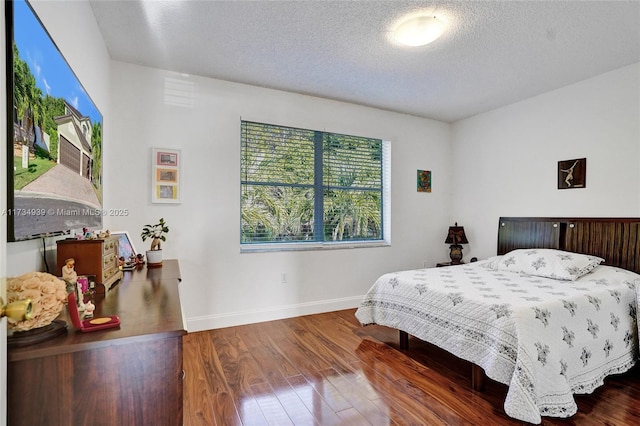 bedroom with dark hardwood / wood-style floors and a textured ceiling