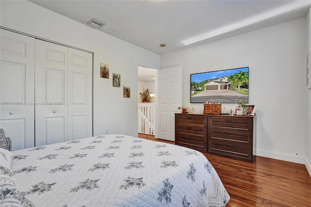 bedroom featuring a closet, dark hardwood / wood-style floors, and a textured ceiling