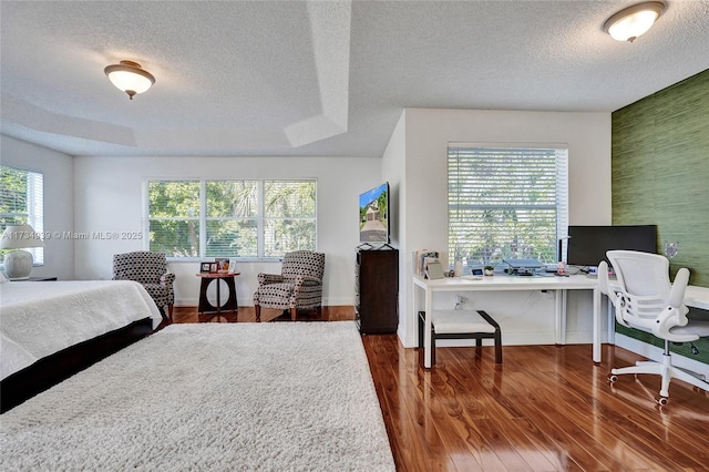 bedroom featuring dark hardwood / wood-style flooring, multiple windows, and a raised ceiling