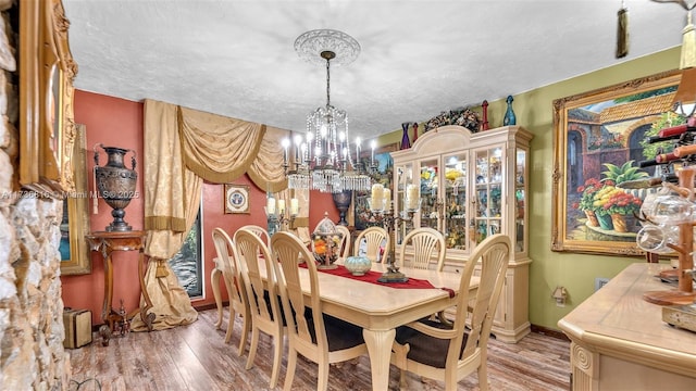 dining room featuring wood-type flooring, a chandelier, and a textured ceiling