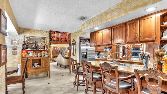 kitchen featuring sink, high end refrigerator, a kitchen breakfast bar, light stone counters, and kitchen peninsula