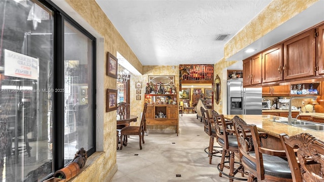 kitchen featuring light stone counters, sink, built in fridge, and a textured ceiling