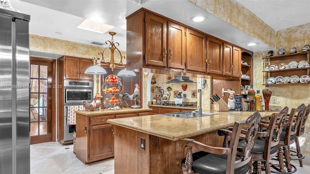 kitchen with a breakfast bar, hanging light fixtures, a skylight, stainless steel appliances, and kitchen peninsula