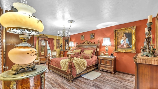 bedroom with hardwood / wood-style flooring, an inviting chandelier, and a textured ceiling