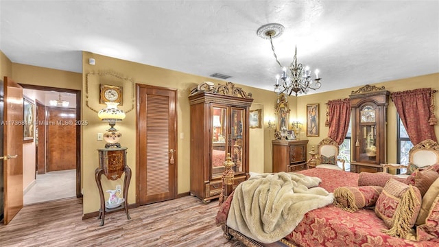 bedroom featuring a textured ceiling, light hardwood / wood-style floors, and a chandelier