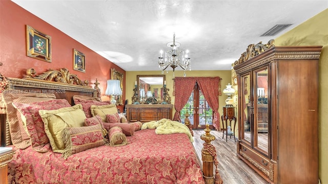 bedroom with hardwood / wood-style floors, a chandelier, access to exterior, a textured ceiling, and french doors