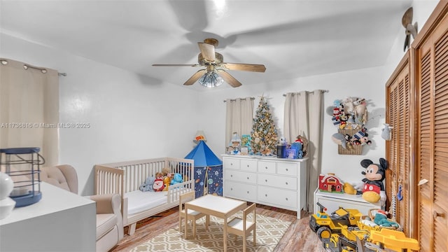 bedroom featuring ceiling fan, a nursery area, light wood-type flooring, and a closet