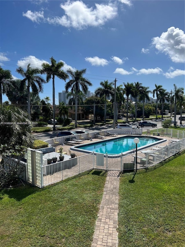 pool with a patio area, a lawn, and fence