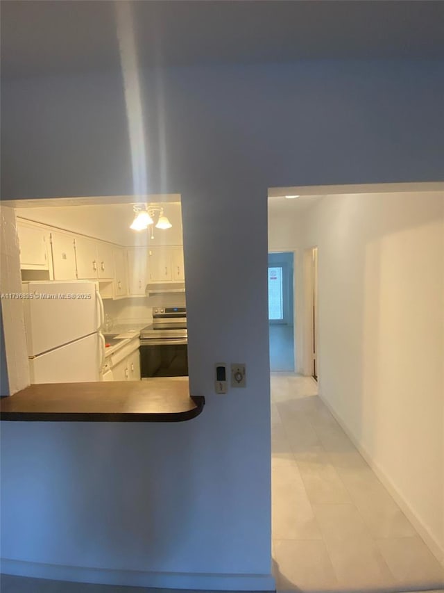 kitchen with under cabinet range hood, white cabinetry, freestanding refrigerator, a peninsula, and stainless steel electric range oven