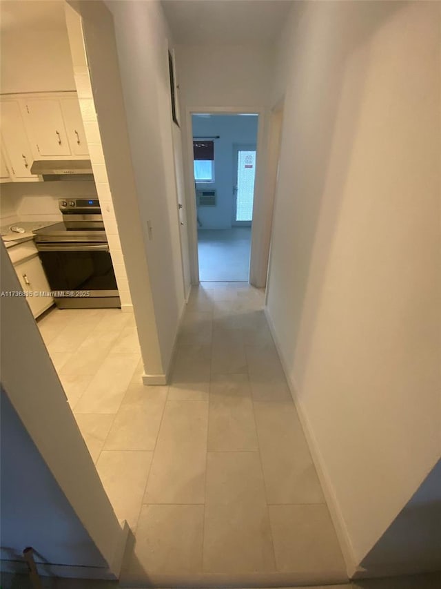 hallway featuring light tile patterned floors and baseboards