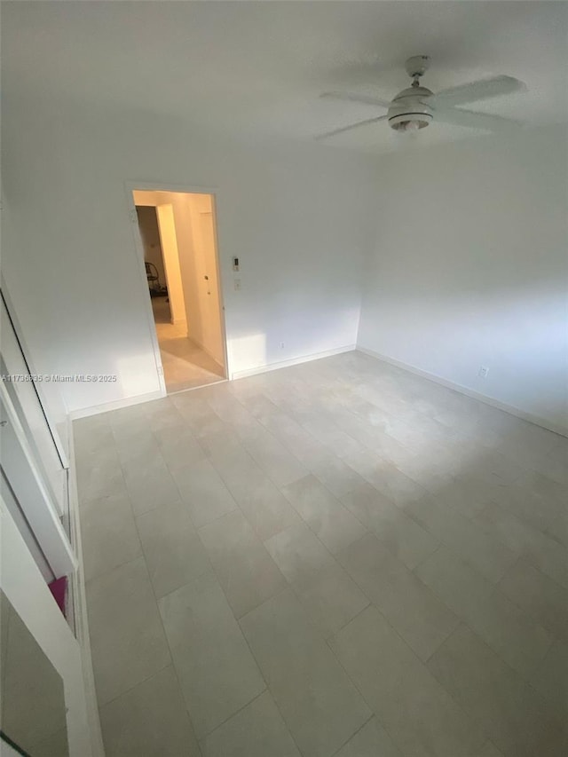 spare room with baseboards and a ceiling fan