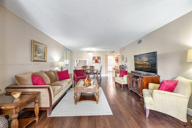 living room featuring dark hardwood / wood-style flooring, a notable chandelier, and a textured ceiling