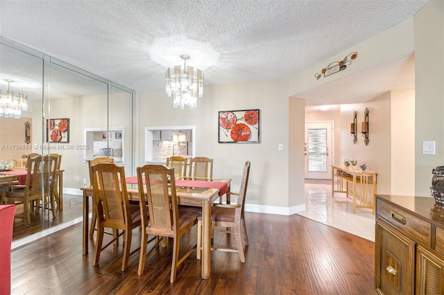 dining room featuring a chandelier, a textured ceiling, dark wood-style floors, and baseboards