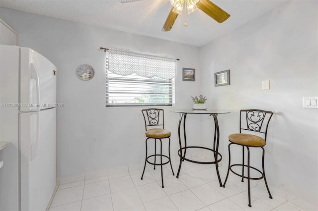 dining area featuring light tile patterned flooring, ceiling fan, and a textured ceiling