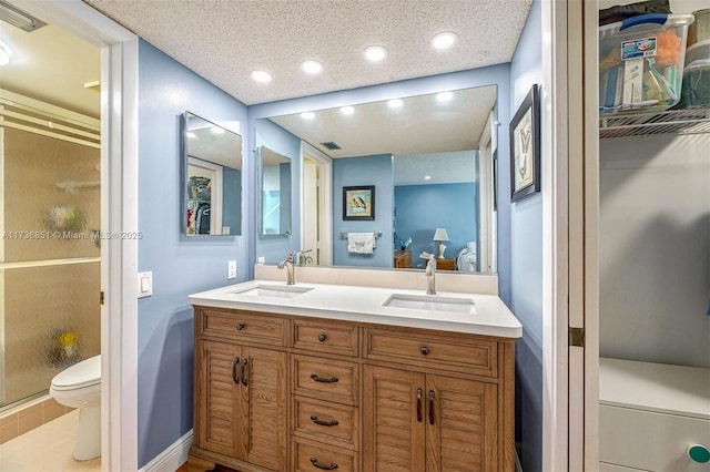 bathroom with vanity, toilet, a shower with door, tile patterned floors, and a textured ceiling